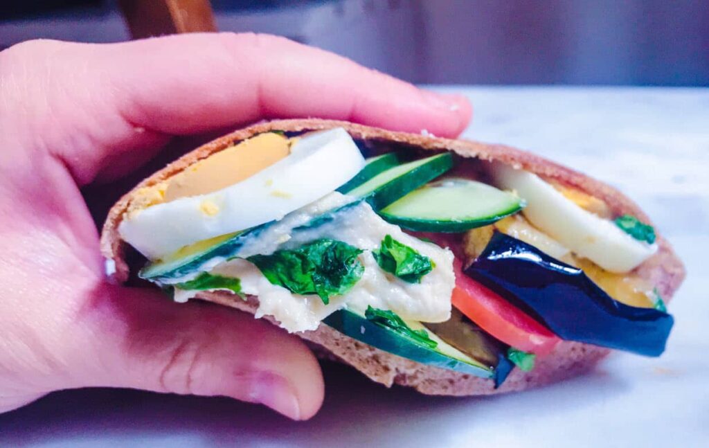 Sándwich Vegano de pan pita con vegetales salteados Hummus verde y