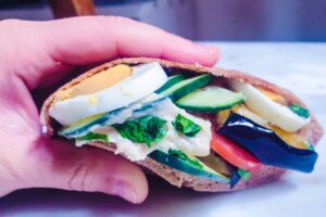 Sándwich Vegano de pan pita con vegetales salteados Hummus verde y ensalada fresca